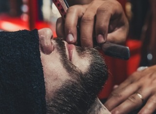 Barber student perfecting a fade on a real client during hands-on 500-hour training