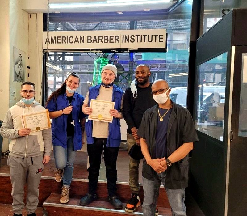 An ABI barber student cutting a real client's hair on the clinic floor in New York City