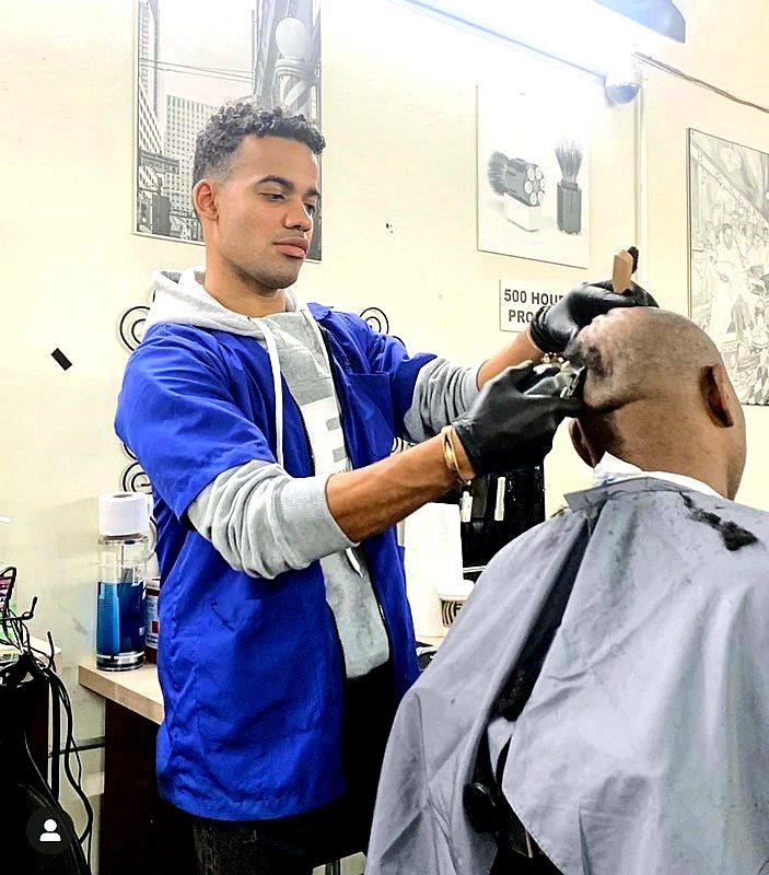 An ABI student practicing a fade on a real client on the barber clinic floor in New York City