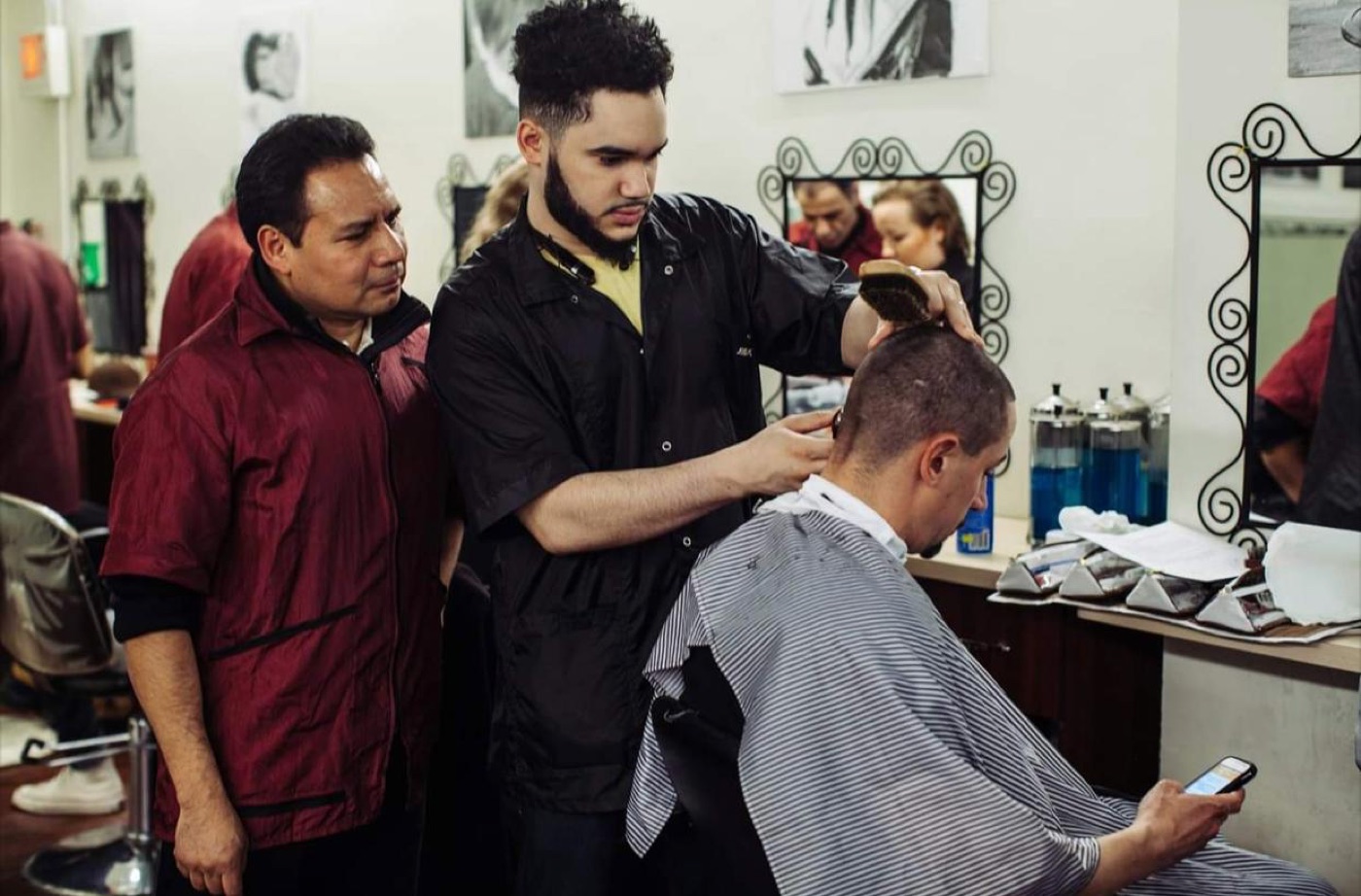 Instructor supervising student's haircut